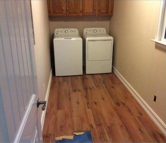 laundry room with standing water on wood floors